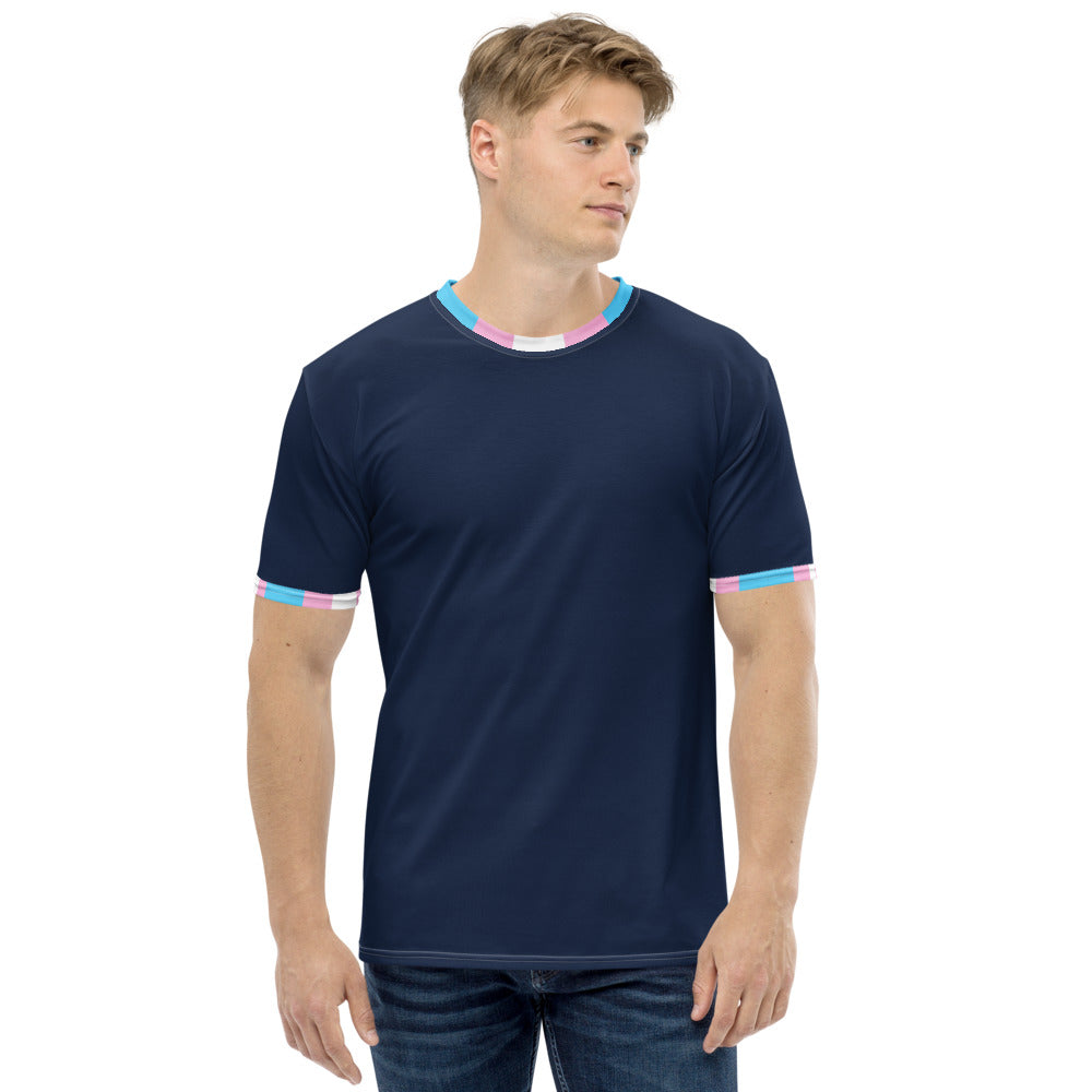 A man wears a blue t-shirt with the collar and cuffs in trans pride flag colours 